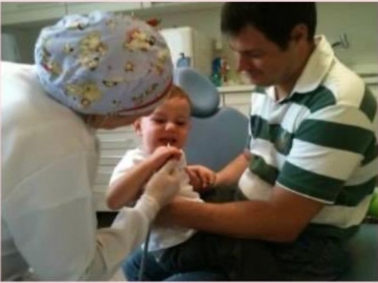 Atendimento de bebê no colo do responsável em consultório odontológico
