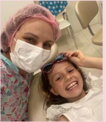 Dra. Aline Guerra sorrindo com uma criança durante o atendimento