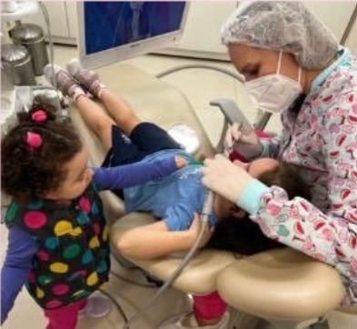 Atendimento odontológico infantil acompanhado por outra criança